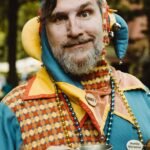 man in orange and white checkered button up shirt wearing blue and yellow hat